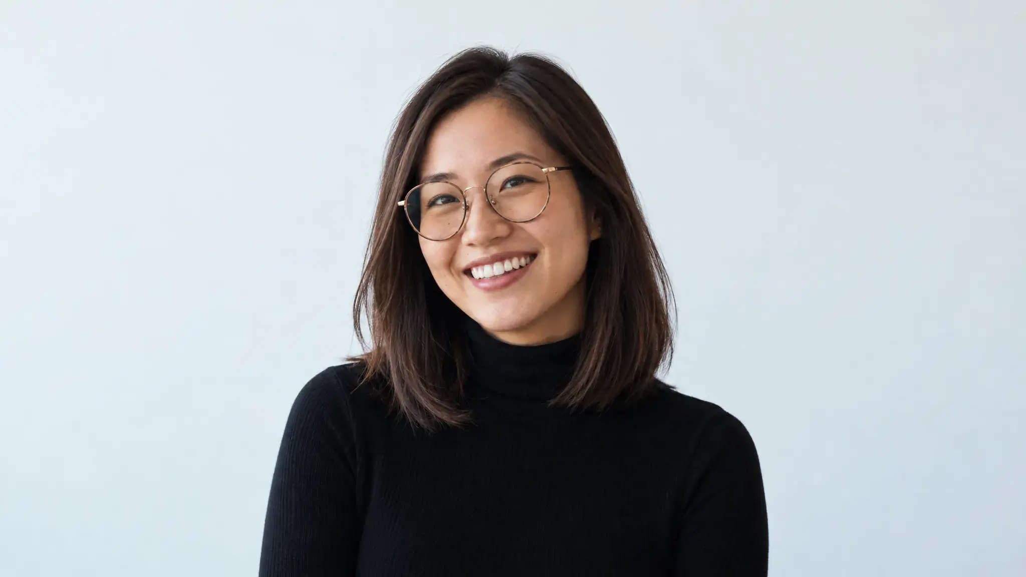 A woman with glasses, smiling at the camera