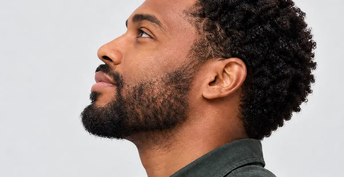 A man with a beard in profile, looking up